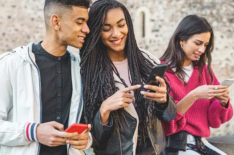 three people looking at mobile devices and smiling