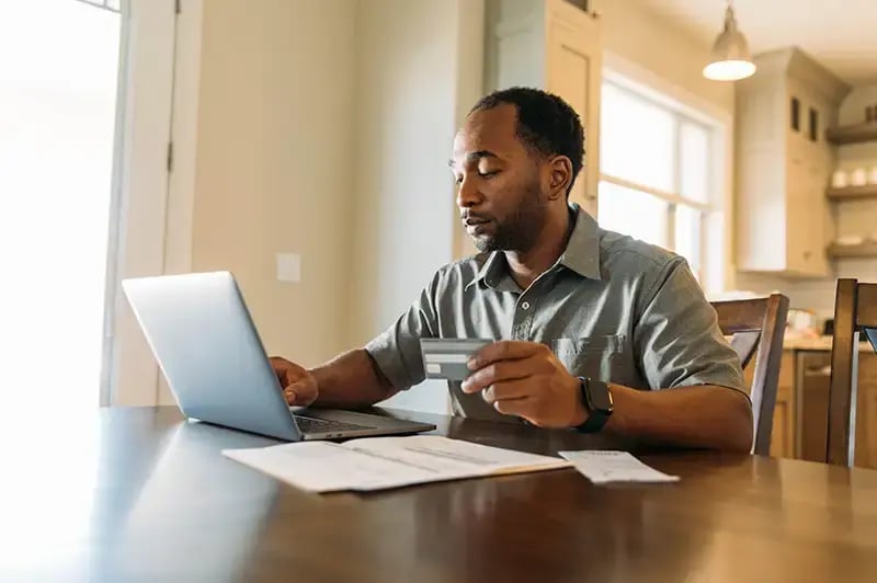 Man using credit card to pay bills on his laptop