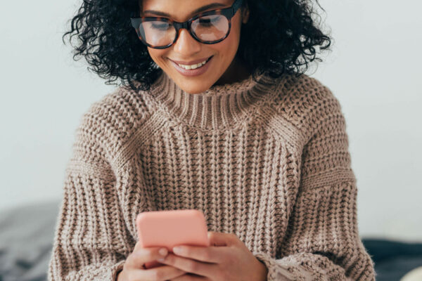 happy woman in sweater looking at her cell phone